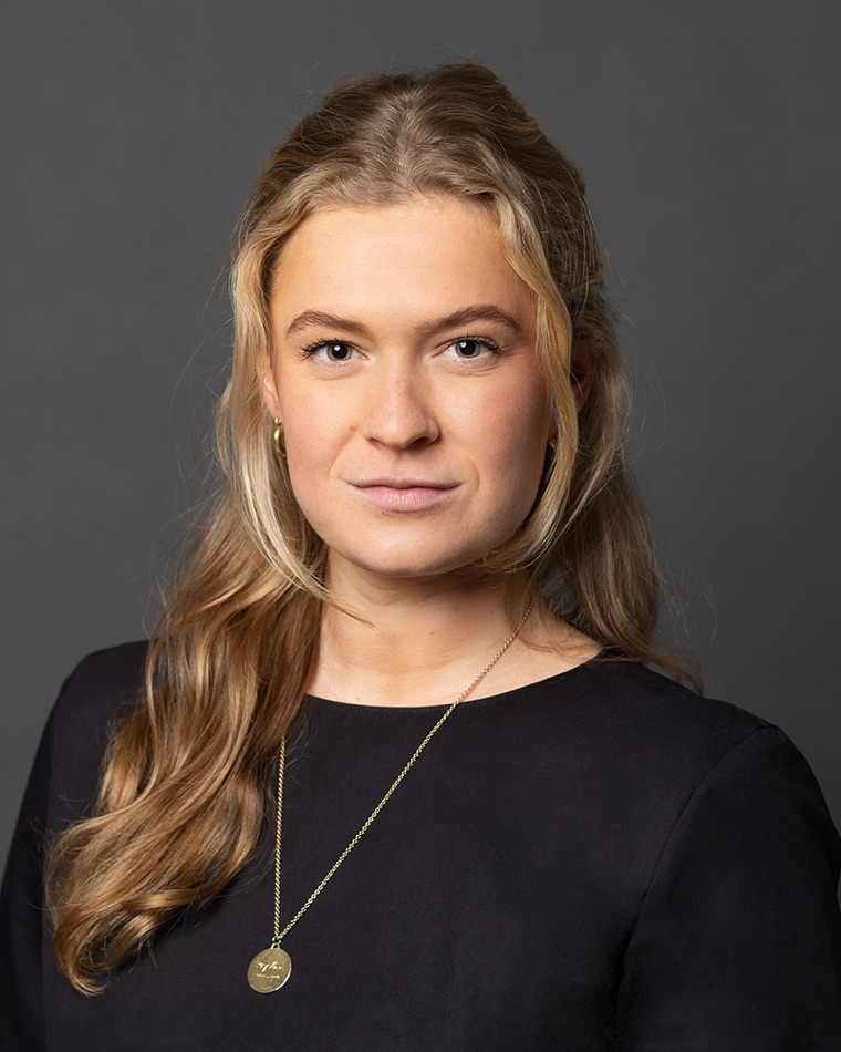 Porträt von Sophie Miller, Gründerin von SAUS, mit langen blonden Haaren und schwarzem Oberteil vor dunkelgrauem Hintergrund